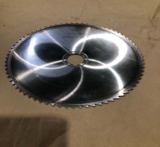 メタルソーの写真です。円形の鉄鋼製工具で、中心に軸を通す穴があり、円周にギザギザの刃があります。回りながら加工物を切断します。