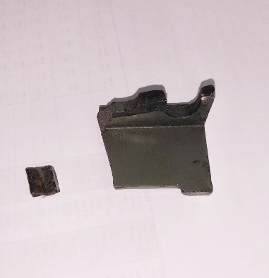 破損したプレートの写真です。破損して装置から外れてしまった部品を写しています。